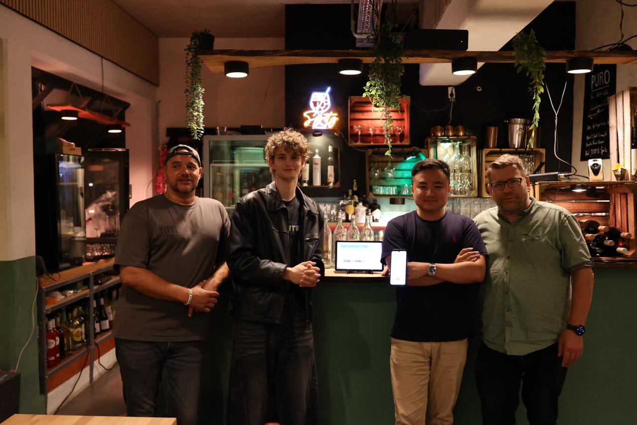 Vier Personen stehen gemeinsam in der PURO Bar vor einer Payline Kasse und einem mobilen Bestellgerät.