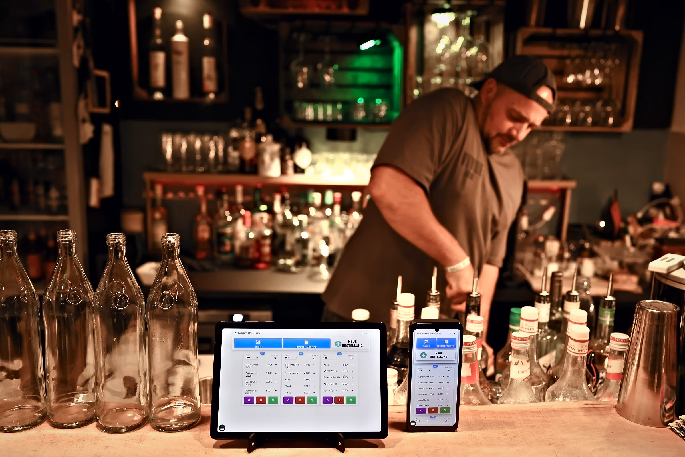Kassentablet und Smartphone mit offenen Tischbestellungen auf dem Tresen einer Bar