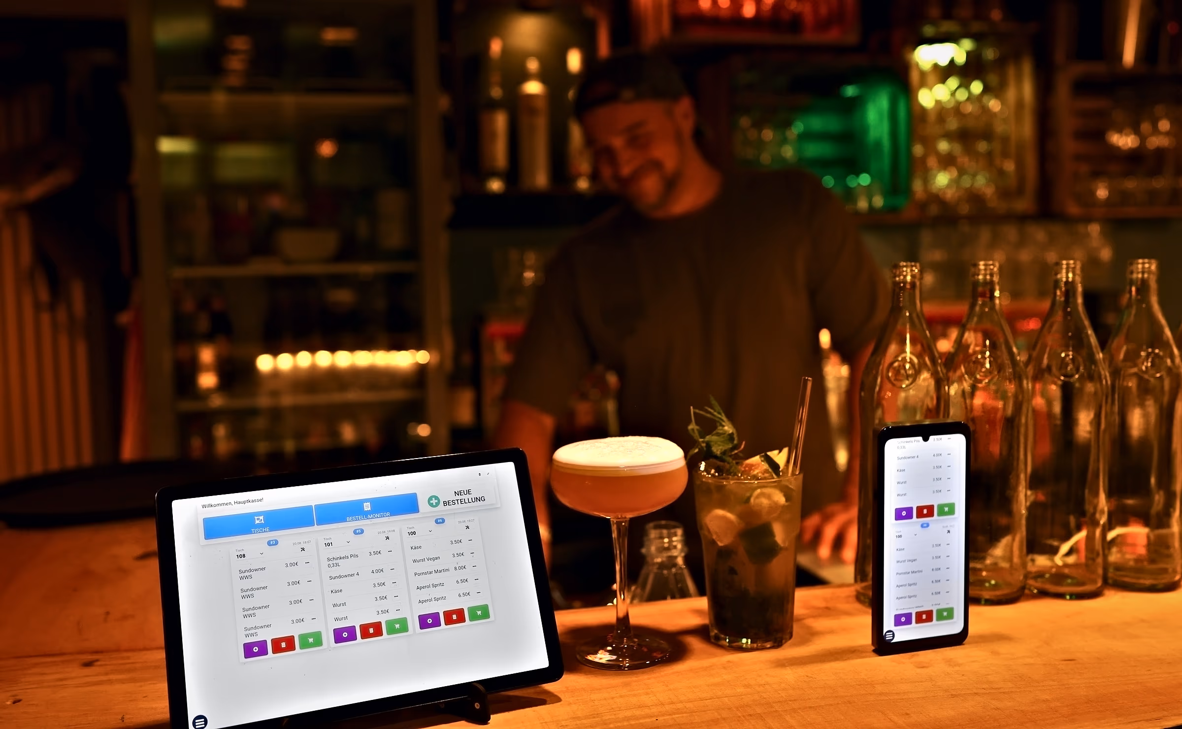 Barkeeper mixt einen Cocktail hinter dem Tresen, daneben die Kasse